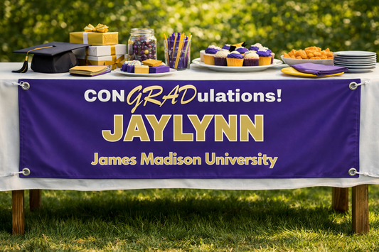 Party table edge — purple & gold banner draped over a decorated graduation table