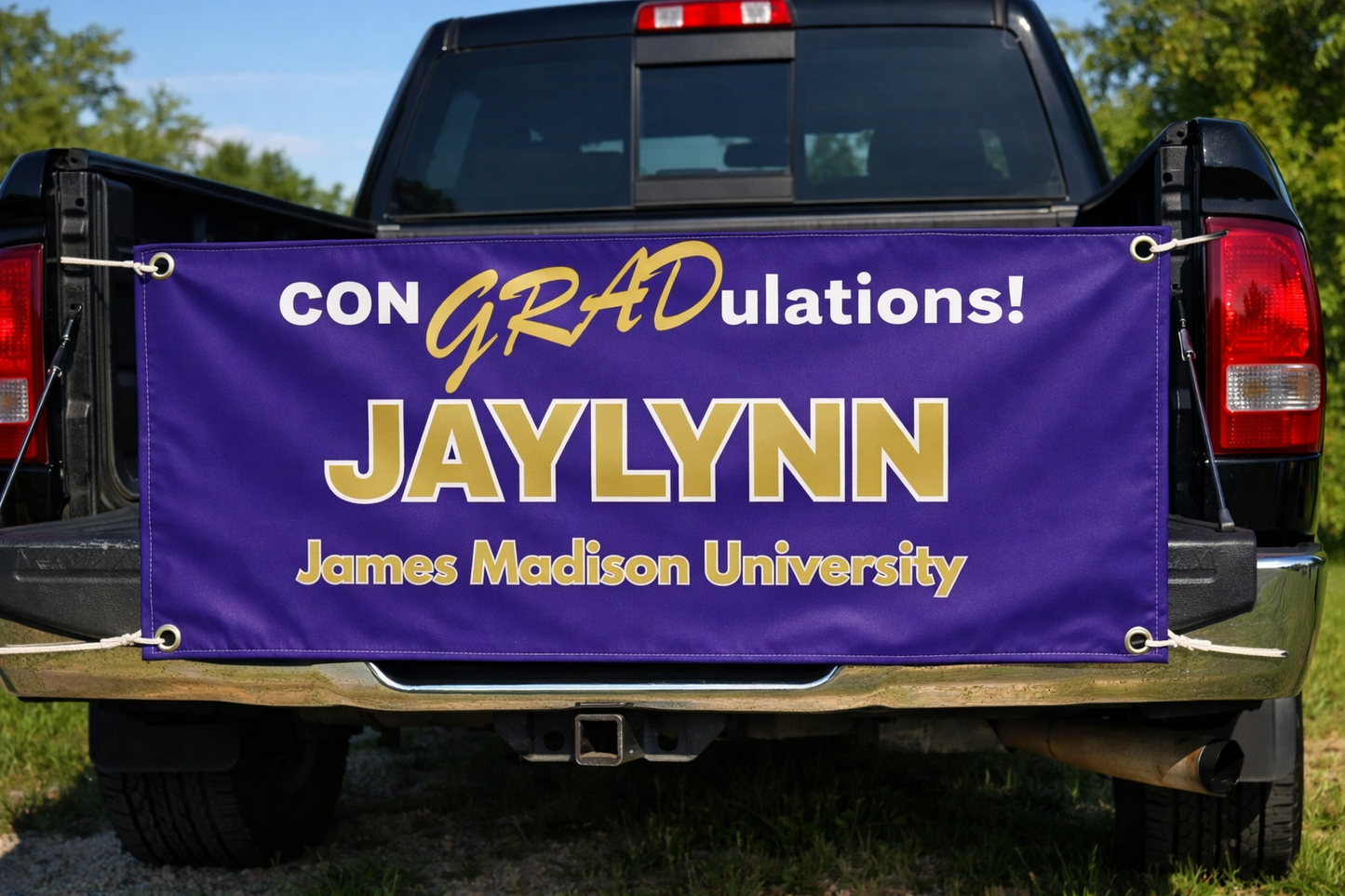 Pickup truck tailgate — banner propped on an open tailgate, sunny outdoor setting