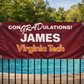 the CONGRADulations banner on a black pool fence with the blue water in the background, grommets and rope on all four corners, looking sharp in the afternoon sun
