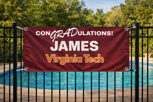 the CONGRADulations banner on a black pool fence with the blue water in the background, grommets and rope on all four corners, looking sharp in the afternoon sun